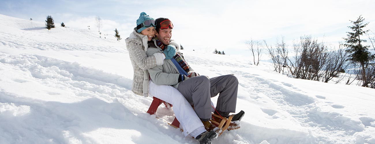 Couple on a sled having fun in the snow